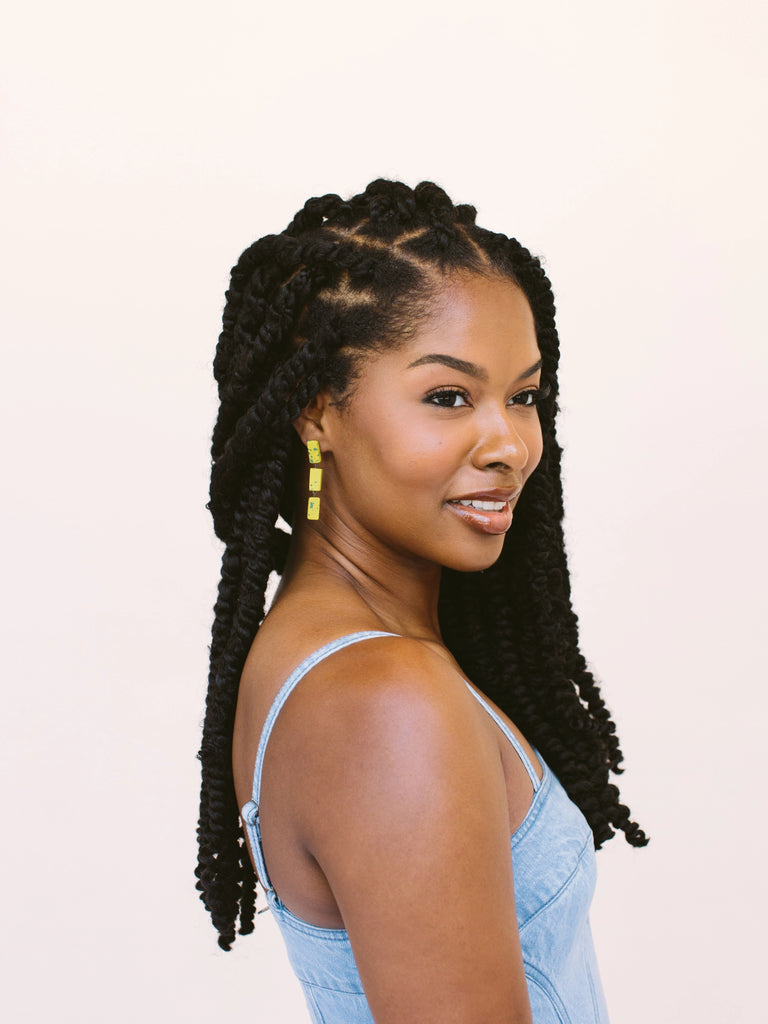 Woman wearing statement earrings in gold with green splatter, handmade locally in Charlotte, NC (North Carolina), at a Plaza Midwood woman owned jewelry art and home decor gift shop. A can't miss thing to do - order a housemade vegan chai at The Chai Window to sip while you shop. 