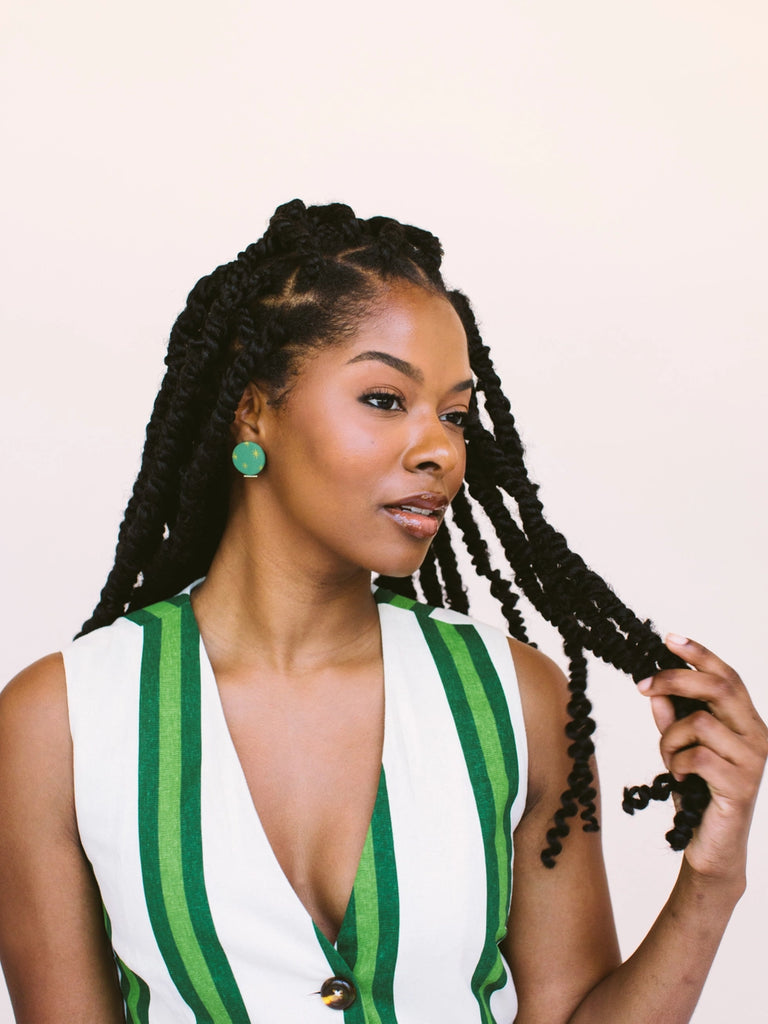 Woman wearing circular emerald green earrings with golden sundance starbursts, handmade locally in Charlotte, NC (North Carolina), at a Plaza Midwood woman owned jewelry art and home decor gift shop. A can't miss thing to do - order a housemade vegan chai at The Chai Window to sip while you shop. 