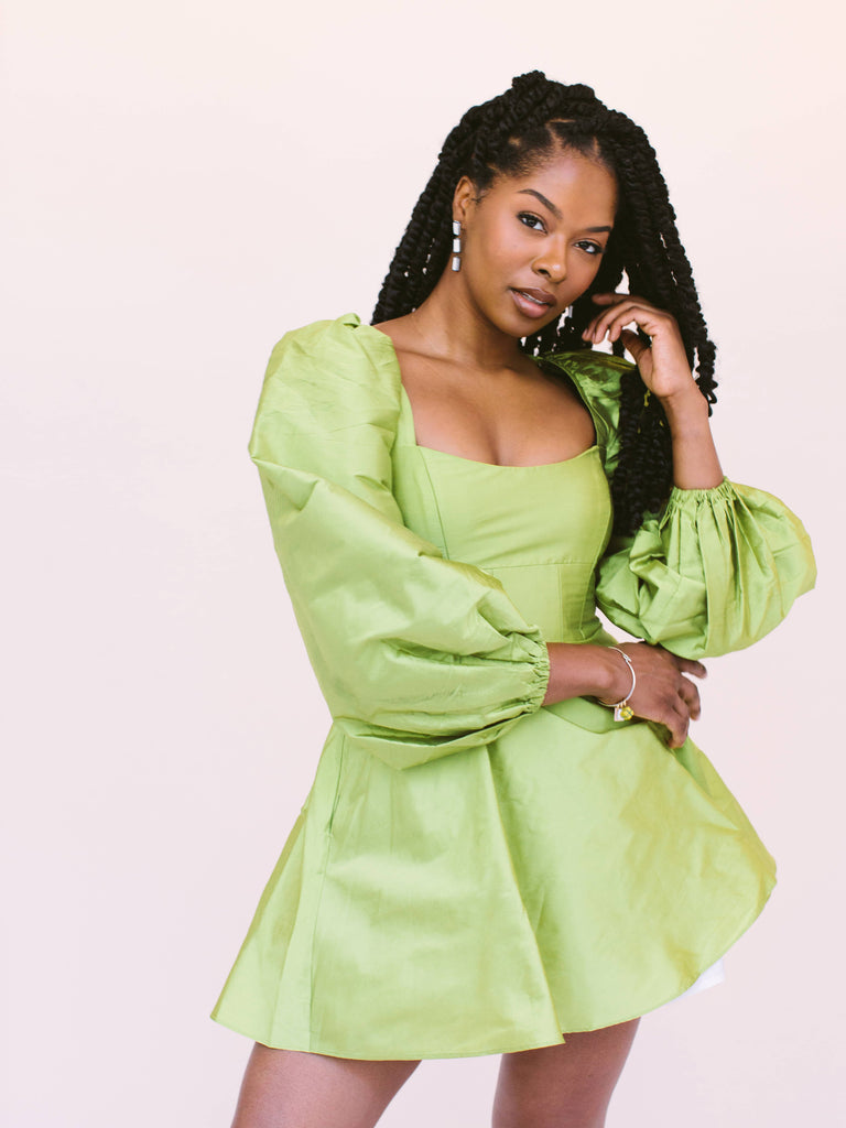 Woman wearing statement earrings in blocked black and white, handmade locally in Charlotte, NC (North Carolina), at a Plaza Midwood woman owned jewelry art and home decor gift shop. A can't miss thing to do - order a housemade vegan chai at The Chai Window to sip while you shop. 