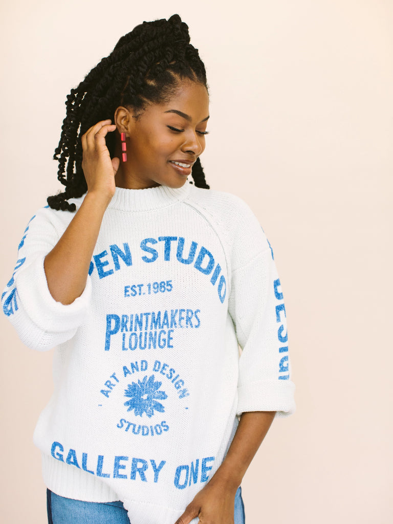 Woman wearing statement earrings in red and burgundy stripes, handmade locally in Charlotte, NC (North Carolina), at a Plaza Midwood woman owned jewelry art and home decor gift shop. A can't miss thing to do - order a housemade vegan chai at The Chai Window to sip while you shop. 