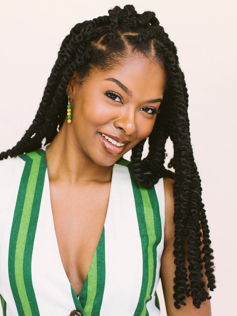 Woman wearing stacking dot earrings in green and gold, handmade locally in Charlotte, NC (North Carolina), at a Plaza Midwood woman owned jewelry art and home decor gift shop. A can't miss thing to do - order a housemade vegan chai at The Chai Window to sip while you shop. 